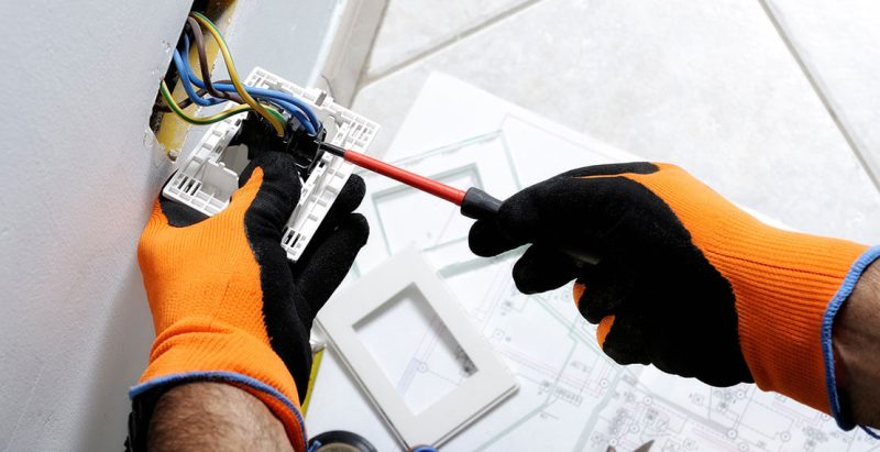 Un tecnico elettrico utilizza un cacciavite per lavorare su un impianto elettrico.