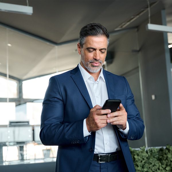 Uomo in abito elegante che utilizza uno smartphone in un ufficio moderno.