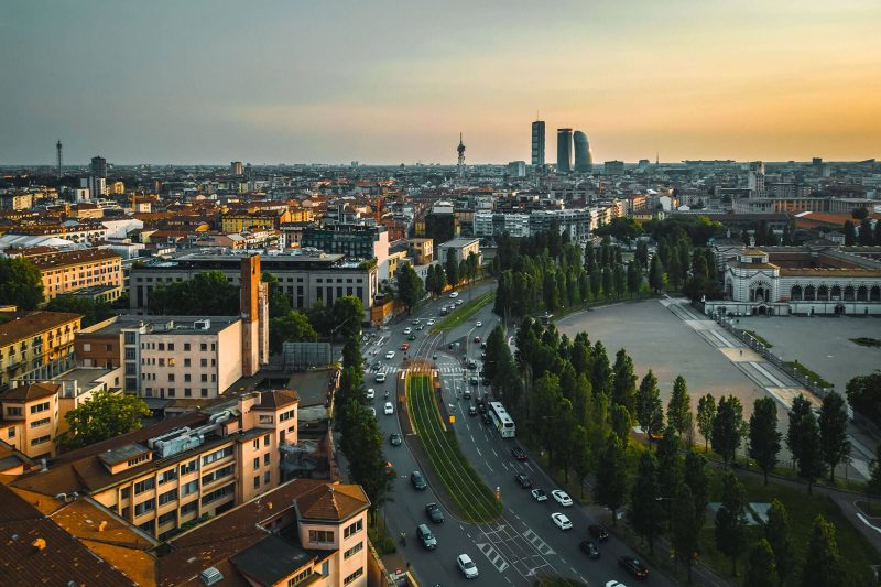 Panorama urbano con edifici, strade e alberi al tramonto.