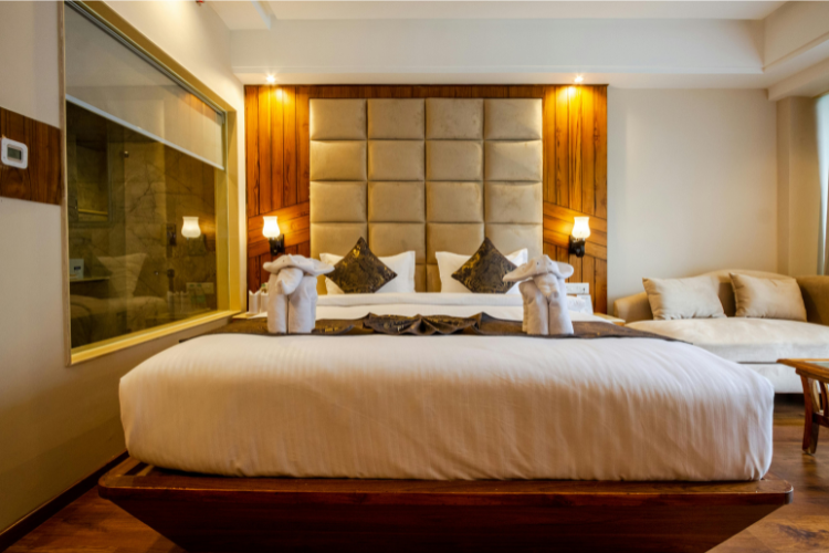 Camera d’hotel elegante con letto matrimoniale, elefanti di asciugamani e arredi moderni.