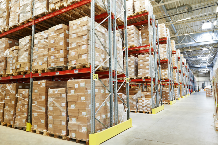 Magazzino con scaffali alti pieni di pallet e scatole, organizzati in file ordinate